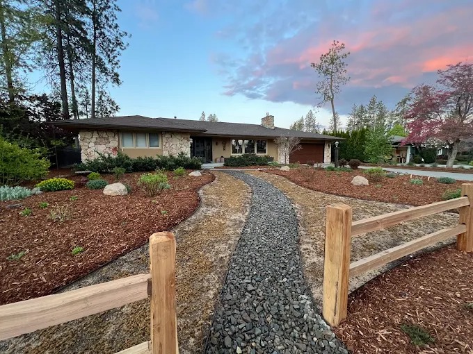 Gravel dry creek bed winding through front yard planting beds at sunset