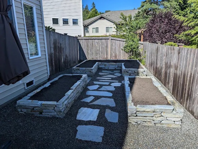 Stacked stone raised garden beds with a flagstone path